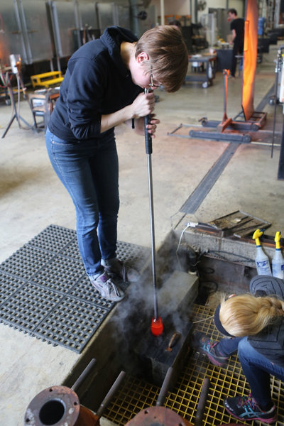 Andrea blowing hot glass into a mold